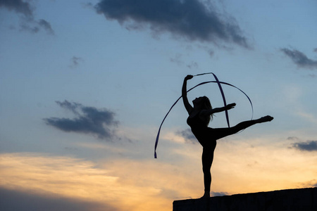 专业体操女舞者,天空背景上有丝带照片