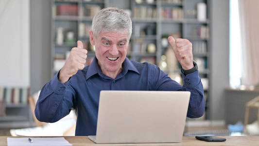 成功人士在办公室用笔记本电脑工作时用拳头庆祝