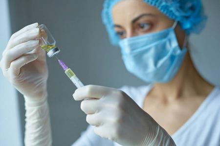 女医生或护士在注射器里灌满液体药物，拿着疫苗。