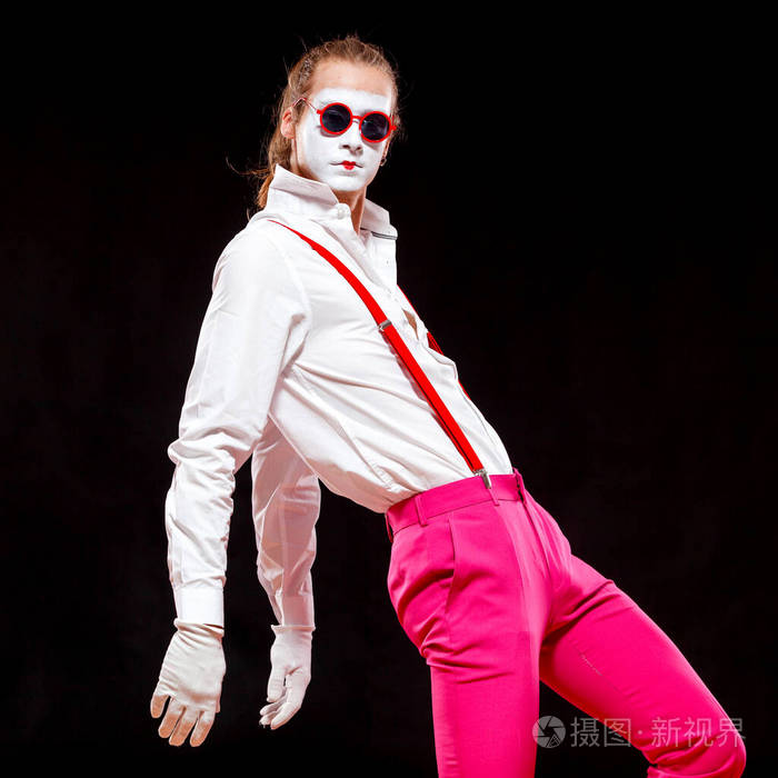 一个穿着吊带裤和粉色裤子的男人正背着双手摆姿势.