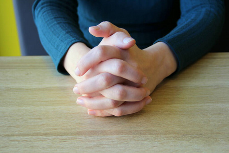 紧握的手指.女孩坐在那里,双手紧握在一起照片