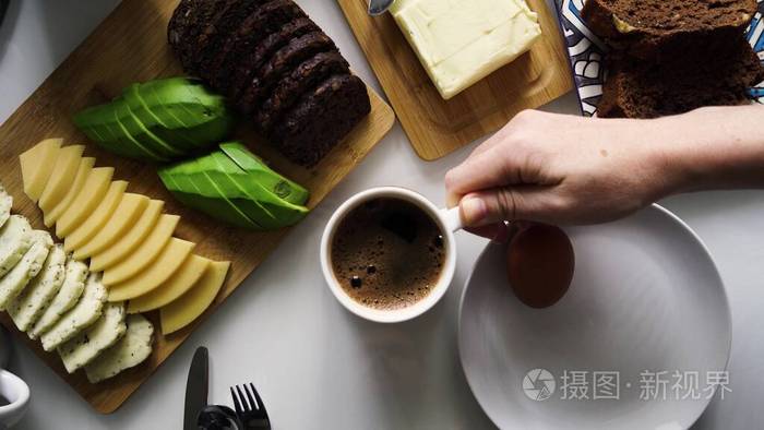 女孩们用手把白色杯子或杯子放在桌子上,杯子里放着黑色芳香的咖