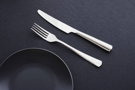 Empty plates and silverware on black background, premium tablewa