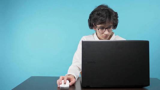 青少年使用笔记本电脑。蓝色背景。网络教育的概念