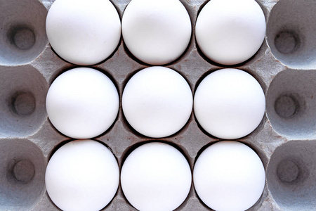 White eggs in a package on a blue background closeup view from 