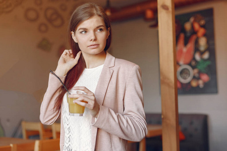 Elegant woman in a pink jacket spend time in a cafe