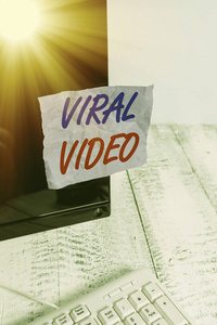 展示病毒视频的概念性手稿。商业照片显示的视频，通过互联网共享符号纸电脑显示器屏幕附近的白色键盘流行。