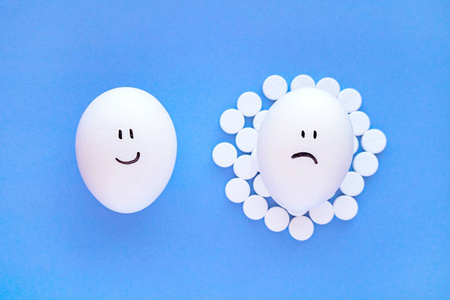 鸡蛋上的笑脸和旁边的白色阿司匹林片。健康和幸福的概念。