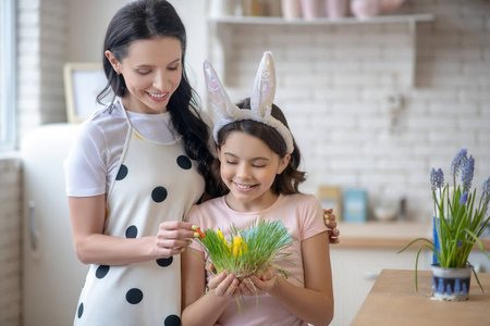 戴着复活节小兔子耳朵的可爱女孩笑着看着复活节彩蛋