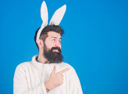 穿着兔子毛绒套装的男人。有胡子和胡子的有趣的兔子男。复活节象征概念。男人胡子时髦可爱温柔兔子长耳朵蓝色背景。尊重传统。复活节兔子