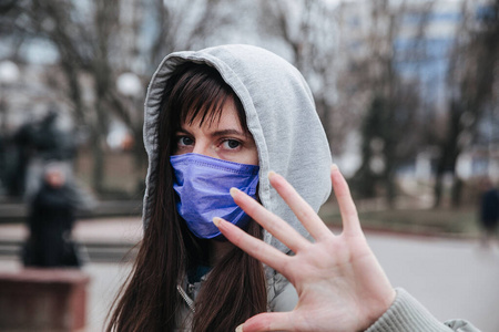 停止感染。女人在做手势停下。图为妇女戴上预防传染病和流感的防护口罩