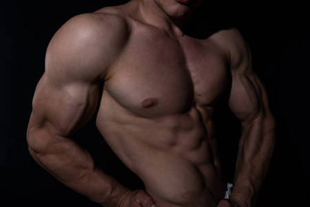 Muscular man showing muscles isolated on the black background. C