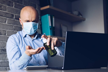 在家工作的男人用抗菌凝胶消毒手。