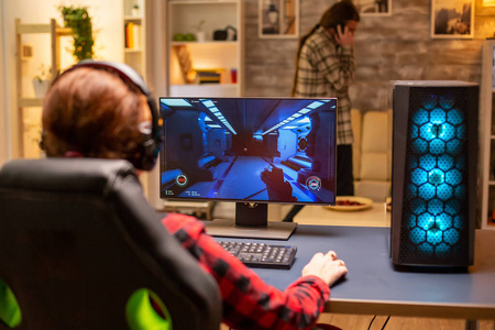 女玩家深夜在客厅里用功能强大的电脑PC玩游戏的后视图