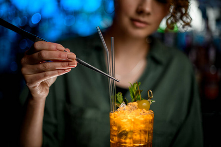 女人用镊子用玻璃棒装饰鸡尾酒图片