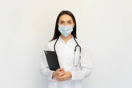 友好的女医生戴着一个带听诊器的医用面罩，手里拿着一个文件夹，