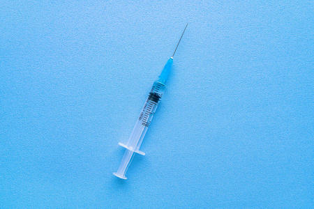 在蓝色背景上隔离冠状病毒疫苗的注射器，有文本特写空间。