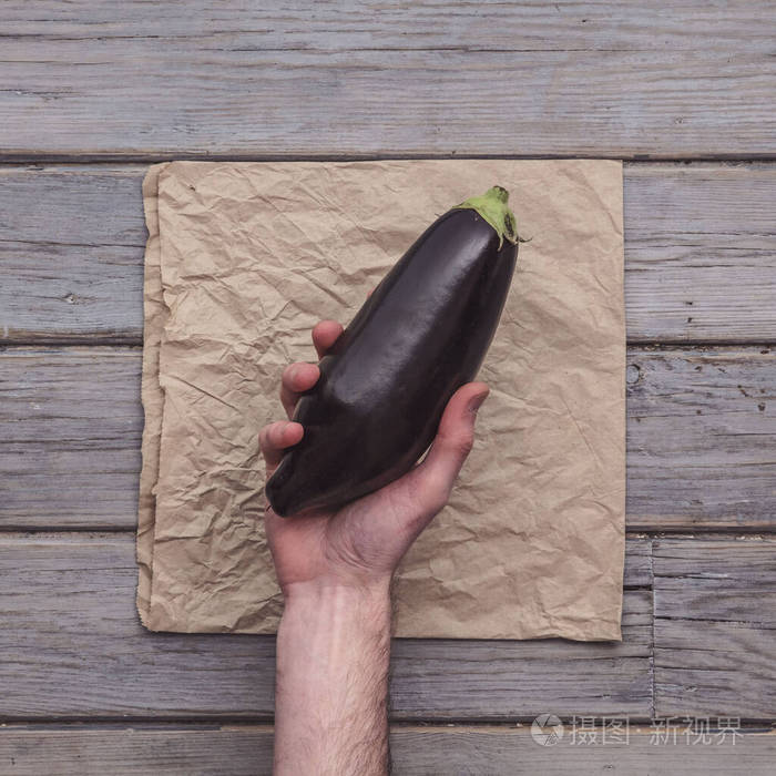 乡村背景下握着新鲜茄子的男性手