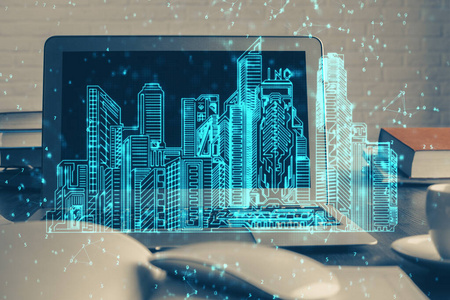桌面电脑背景办公楼和大城市建筑全息图绘制。双重曝光。智慧城市概念。