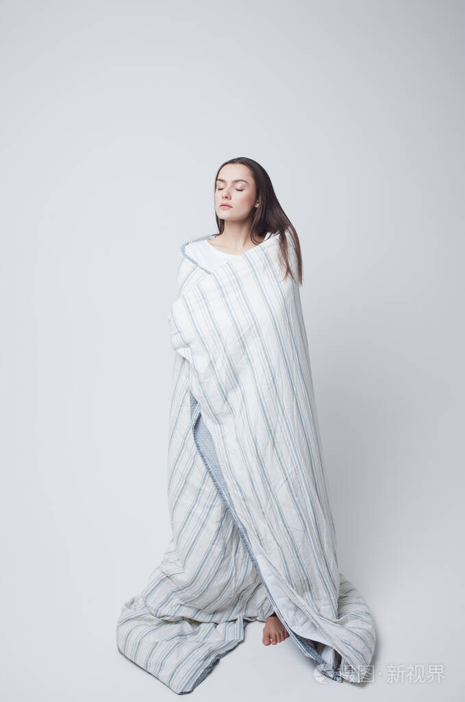 健康的睡眠和困倦美丽的年轻女子裹着毯子站着