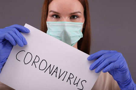 Woman holds a white list of paper with sign coronavirus.