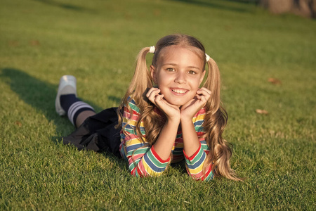 享受学生生活过着幸福的生活.玩得高兴.女孩躺在绿草丛中.