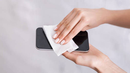 女孩用餐巾擦拭智能手机,全景,自由空间照片