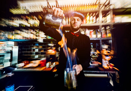 The bartender makes a cocktail with a fire show at the bar. 