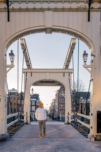荷兰阿姆斯特丹城市之旅的年轻人，带着古老的运河房屋和桥梁参观阿姆斯特丹的运河