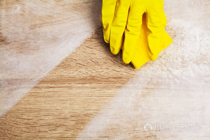 戴黄色手套的工人在办公室里擦灰尘的特写镜头