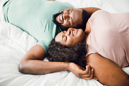 高兴的年轻夫妇躺在床上微笑着合影