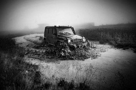 在一片泥泞的乡村风景中，车轮特写。乡下的越野车在雨后陷在了无法通行的路上。
