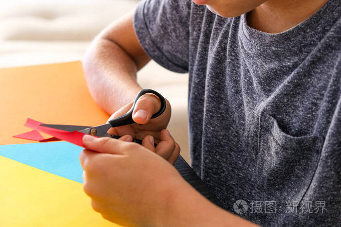 儿童纸制工艺品孩子们在桌边用剪刀剪彩纸