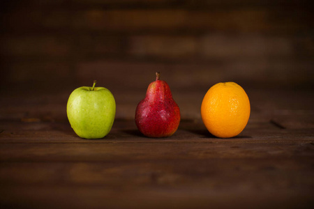 苹果梨和橘子放在一张木桌上。