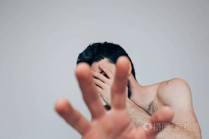 这个年轻人被孤立在幕后照片中的男子用手捂住脸并显示另一个靠近镜头