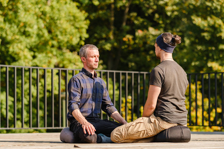 A group of young people meditate outdoors in a park. 