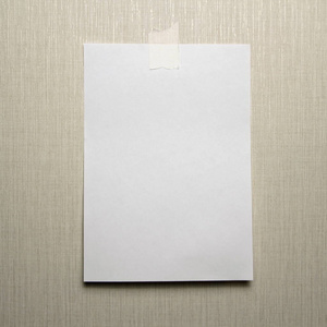 挂着空白的笔记标记墙上挂着一张a4白纸,用胶带粘在浅色背景上照片