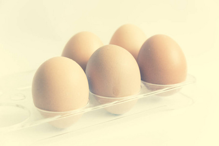 工作室拍摄了五个棕色的生鸡蛋在白色隔离的塑料包装上照片