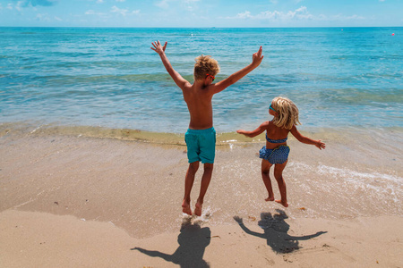 快乐的男孩和女孩在热带海滩上玩耍