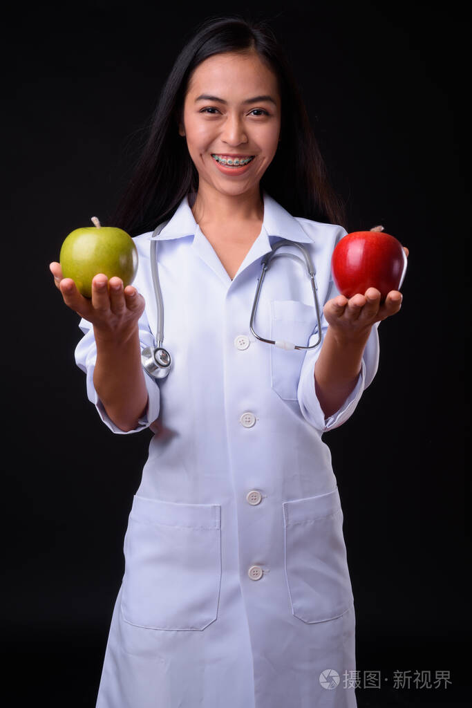 快乐的年轻亚洲女医生拿着两个苹果当营养师