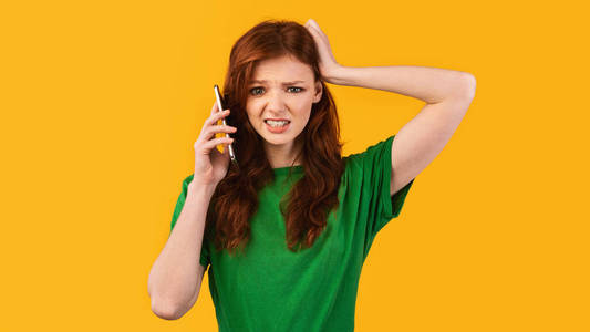 抓狂困惑的女孩在打手机抓狂,全景,摄影棚拍摄照片