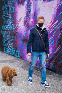 Man walks dog wearing face mask protection 