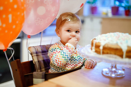 可爱的小女孩庆祝一岁生日。自制蛋糕上的婴儿吃棉花糖装饰，室内。可爱的幼儿，漂亮的女儿的生日聚会