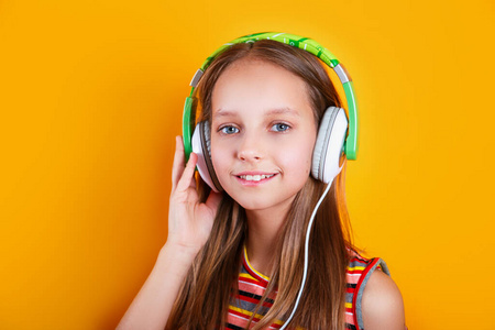 快乐微笑的女孩喜欢在橙色背景下戴着耳机听音乐