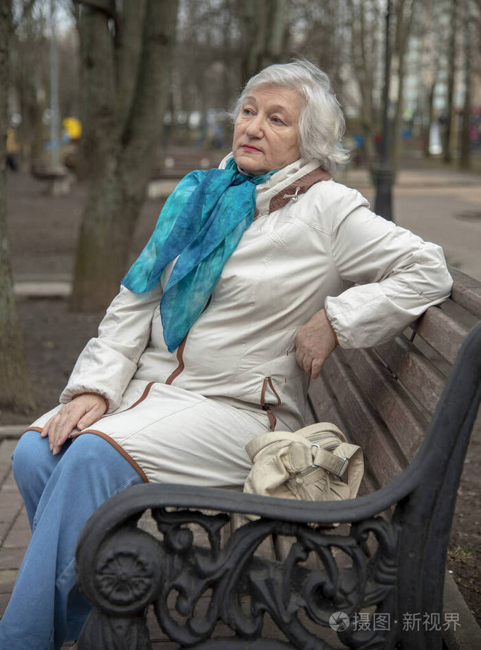 一位优雅的白发老人坐在公园的长椅上