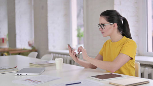 年轻女设计师上班用智能手机