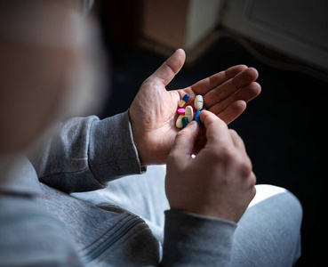 一个蒙面男子手里拿着五颜六色的药丸.世界大流行性冠状病毒.