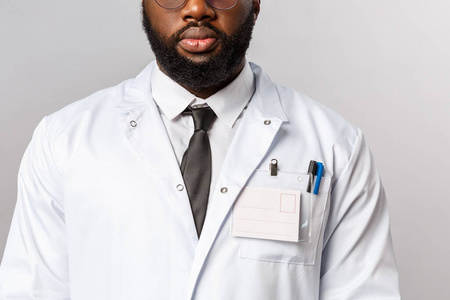 医疗保健医学和医院治疗理念。一个留着胡子的非裔美国医生，穿着白大褂，打着领带，穿着制服在诊所治疗病人