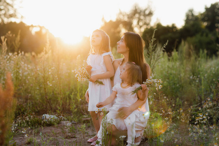 生活方式肖像画妈妈和两个女儿在外面的草地上