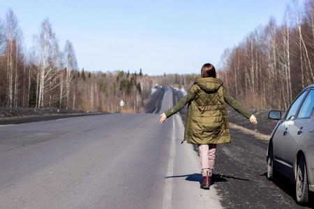一个年轻女子走在路边。森林里的路